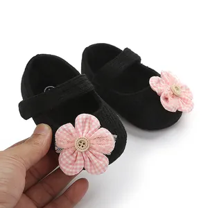 Vista detallada de zapatos negros para bebé niña con flor de cuadros rosa y botón de madera.