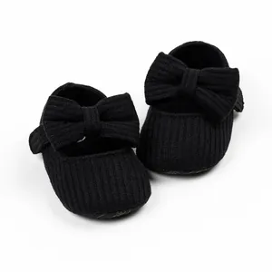 Detailed view of black ribbed infant pre-walker shoes with large bow accents.