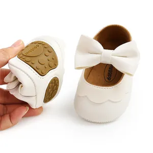 Close-up of white baby princess shoes with a large bow and soft flexible sole