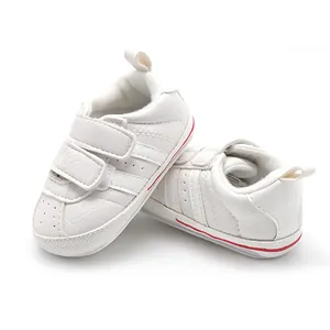 Detailed side view of white infant walking shoes with double hook-and-loop straps