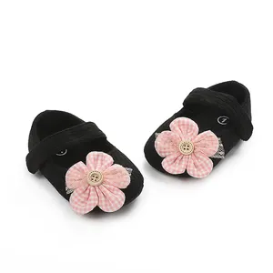 Detalle de zapatos de gateo para niña negros con flores de cuadros rosa.