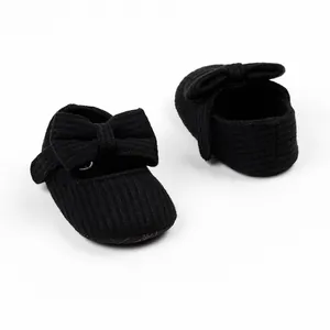 Detailaufnahme von schwarzen gestrickten Babyschuhen für Mädchen mit Schleifen-Akzent