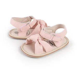 Detailed view of pink infant walking sandals with a cute knot design and Velcro strap.