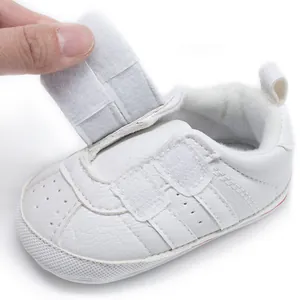 Close-up of white infant walking shoe featuring adjustable Velcro strap and soft sole