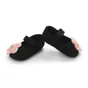 Primer plano de zapatos de bebé negros con decoración de flor rosa y detalle de botón