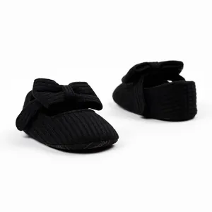 Nahaufnahme von schwarzen gestrickten Babyschuhen für Mädchen mit dekorativer Schleife