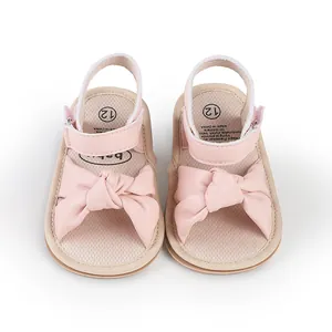 Macro detail of pink baby pre-walker sandals featuring a large soft decorative bow