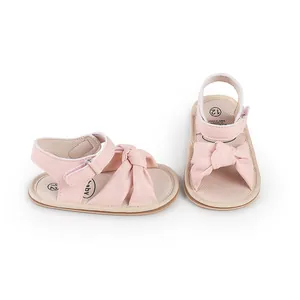 Detailed macro view of soft pink leather baby walking sandals with a decorative bow