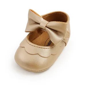 Close-up of gold baby walker shoe with a large bow and soft PU leather texture.