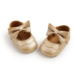 Detailed view of champagne gold baby princess shoes with a large decorative bow