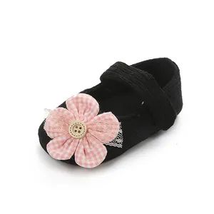 Detalle de zapato negro para bebé con un adorno de flor a cuadros de color rosa