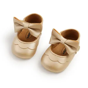 Detailed view of champagne gold baby princess shoes featuring a large bow and soft sole