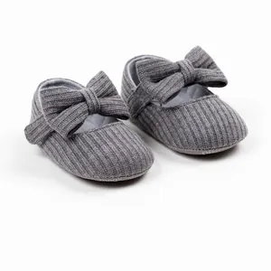 Close-up detail of grey ribbed fabric infant girl walker shoes with large bowknot.