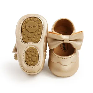 Detailed close-up of gold metallic PU baby shoes with large bow and soft rubber grip sole