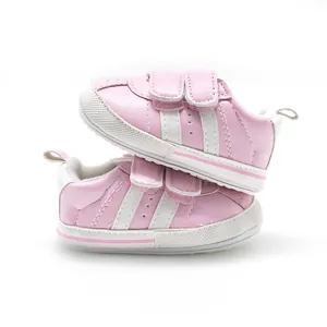Detailed side view of pink baby walking shoes with two white stripes and velcro.