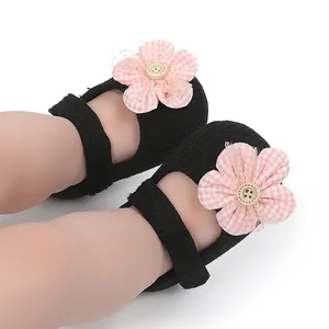 Primer plano de zapatos de bebé niña negros con decoración de flor de cuadros vichy rosa
