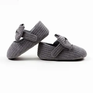 Detailed macro view of gray knitted baby princess shoes with bow and velcro strap.