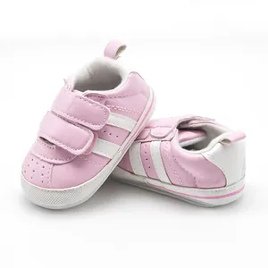Side view of pink baby sneakers with white stripes and hook and loop closure