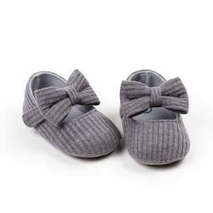 Close-up of grey ribbed knit baby girl princess walking shoes with a large bow detail