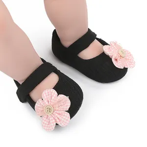 Detalle de zapatos para bebé de punto negro con flor a cuadros rosa