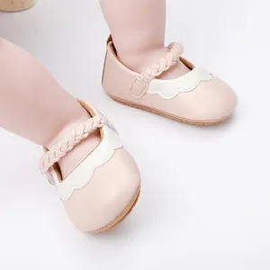 Nahaufnahme von rosa Baby-Lauflernschuhen mit geflochtenen Riemen und Wellenrand.