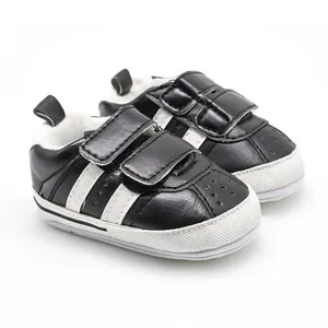 Close-up view of black and white baby walking shoes with dual Velcro straps and rubber sole