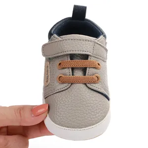 Detailed view of grey baby walking shoes with brown elastic laces and velcro strap