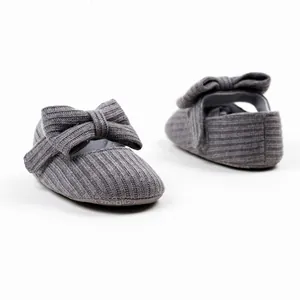 Detailed view of soft grey knitted baby walking shoes with large bow for infant girls.