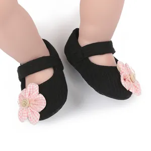 Close-up of soft black knitted baby princess shoes featuring pink floral decor