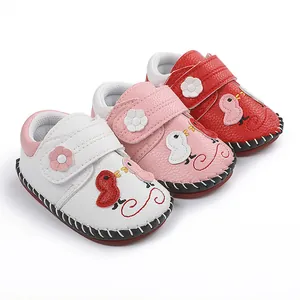 Vista detallada de zapatos para caminar de bebé cosidos a mano en blanco rosa y rojo