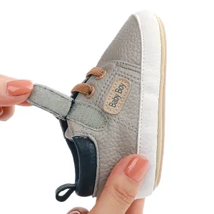 Close-up of baby walking shoe showing Velcro strap and soft grey leather texture