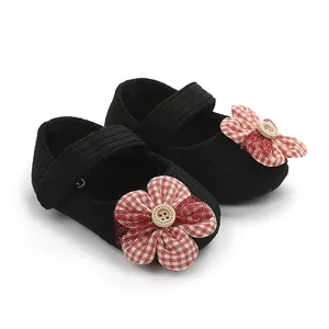 Primer plano de zapatos de bebé para niña con flor de cuadros rojos y un botón de madera