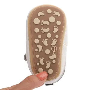 Detailed view of the anti-slip rubber sole on a white infant pre-walker baby shoe