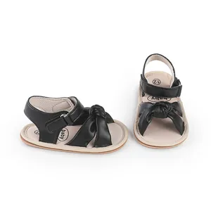 Black synthetic leather baby walker sandals featuring a large bow knot and adjustable strap