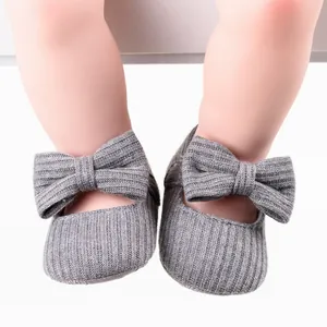 Close-up view of grey knit baby walking shoes with a decorative bow for infant girls