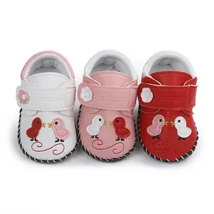 Tres pares de zapatos de bebé cosidos a mano en colores blanco, rosa y rojo con dibujos