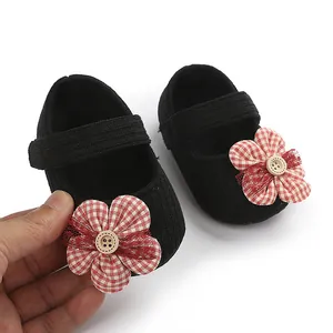 Primer plano de zapatos para bebé niña con flor de cuadros rojos y botón de madera