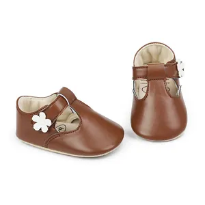 Close-up detail of brown baby girl Mary Jane shoes featuring a white flower accent