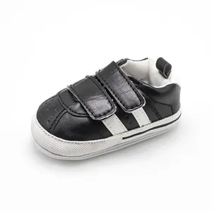 Close-up of black baby walker shoes with white stripes and velcro straps