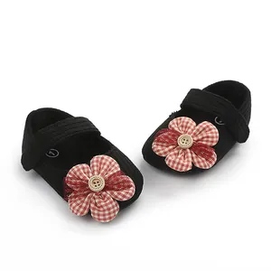 Detalle de zapatos de gateo para bebé niña en negro con flor de cuadros rojos