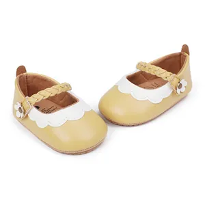 Nahaufnahme gelbe Baby-Lauflernschuhe mit weißem Wellenrand und geflochtenen Blumenriemen