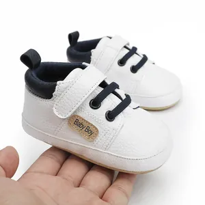 Detailed view of white faux leather baby boy pre-walker shoe with soft sole held in palm