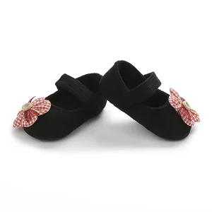 Primer plano de zapatos de punto negro para bebé con detalles de flores a cuadros