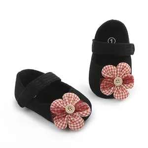 Detalle de zapatos de bebé niña negros con flor de cuadros rojos y botón de madera