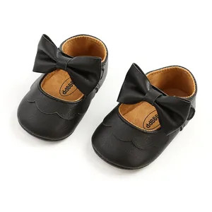 Macro view of black PU leather toddler shoes featuring a large bow and scalloped toe