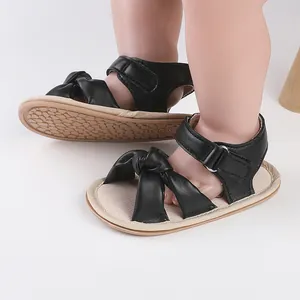 Close-up of black faux leather baby sandals with bow-knot and hook-and-loop strap