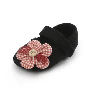 Primer plano de zapato de bebé niña con flor a cuadros rojos y detalle de botón