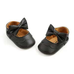 Close-up of black PU leather baby shoes with elegant bow detailing and soft soles.