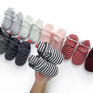 Main tenant des chaussons rayés pour bébé avec diverses couleurs en arrière-plan pour l'hiver.