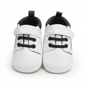 Close-up of white baby walker shoes with navy blue accents and velcro strap detail.